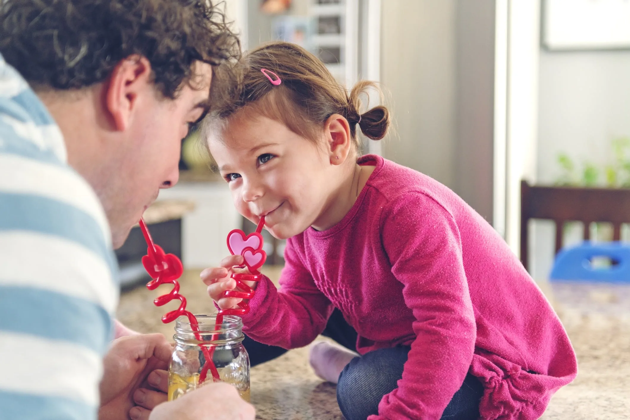man and little girl sipping drink from bendy straws