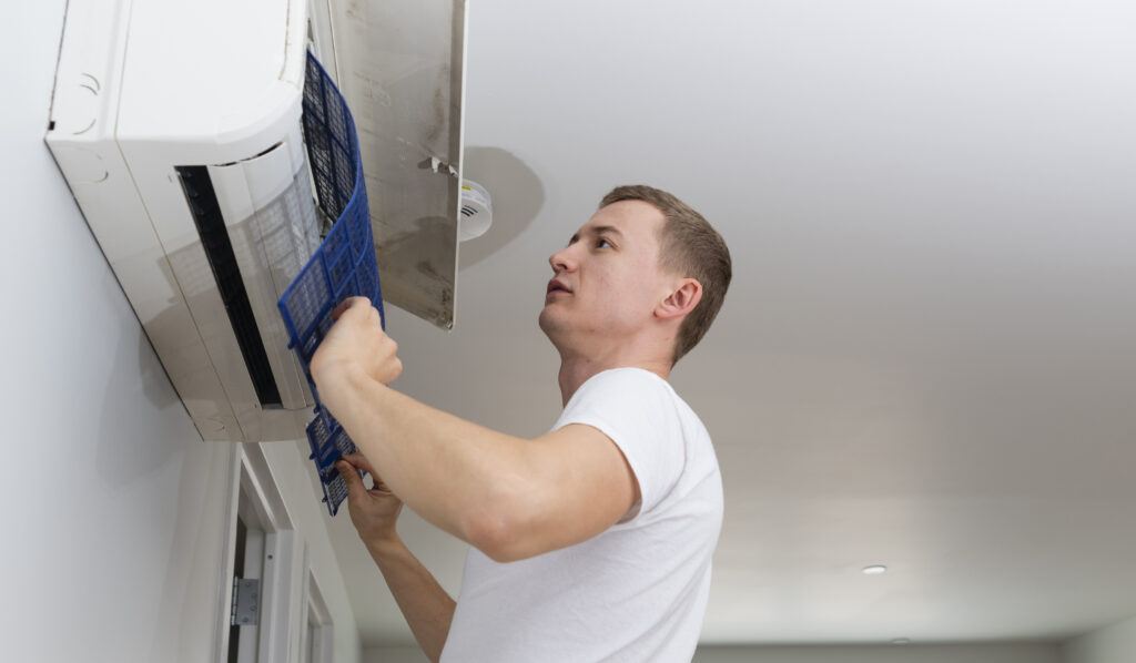 Young man cleaning filters in the air-conditioning split device.